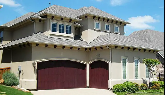 large dark wood garages on nice house. one single and one double both wood doors