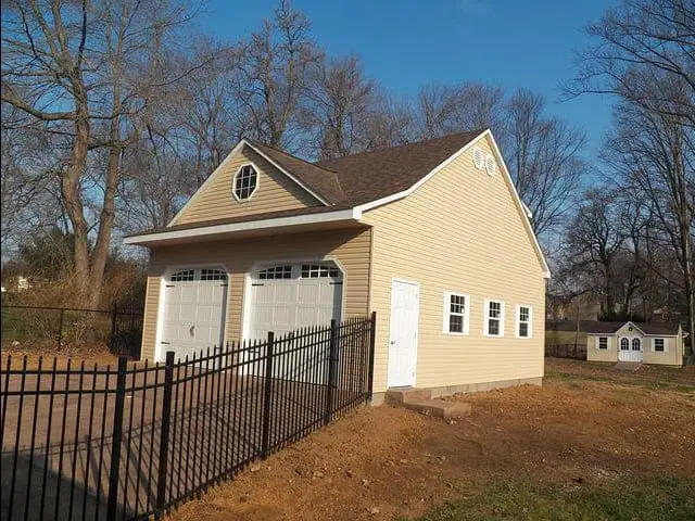 two single garage doors white with windows on yellow detached garage